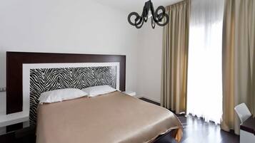 A hotel room with a zebra-patterned headboard, a bed with a beige cover, a modern light fixture, and a window with curtains.