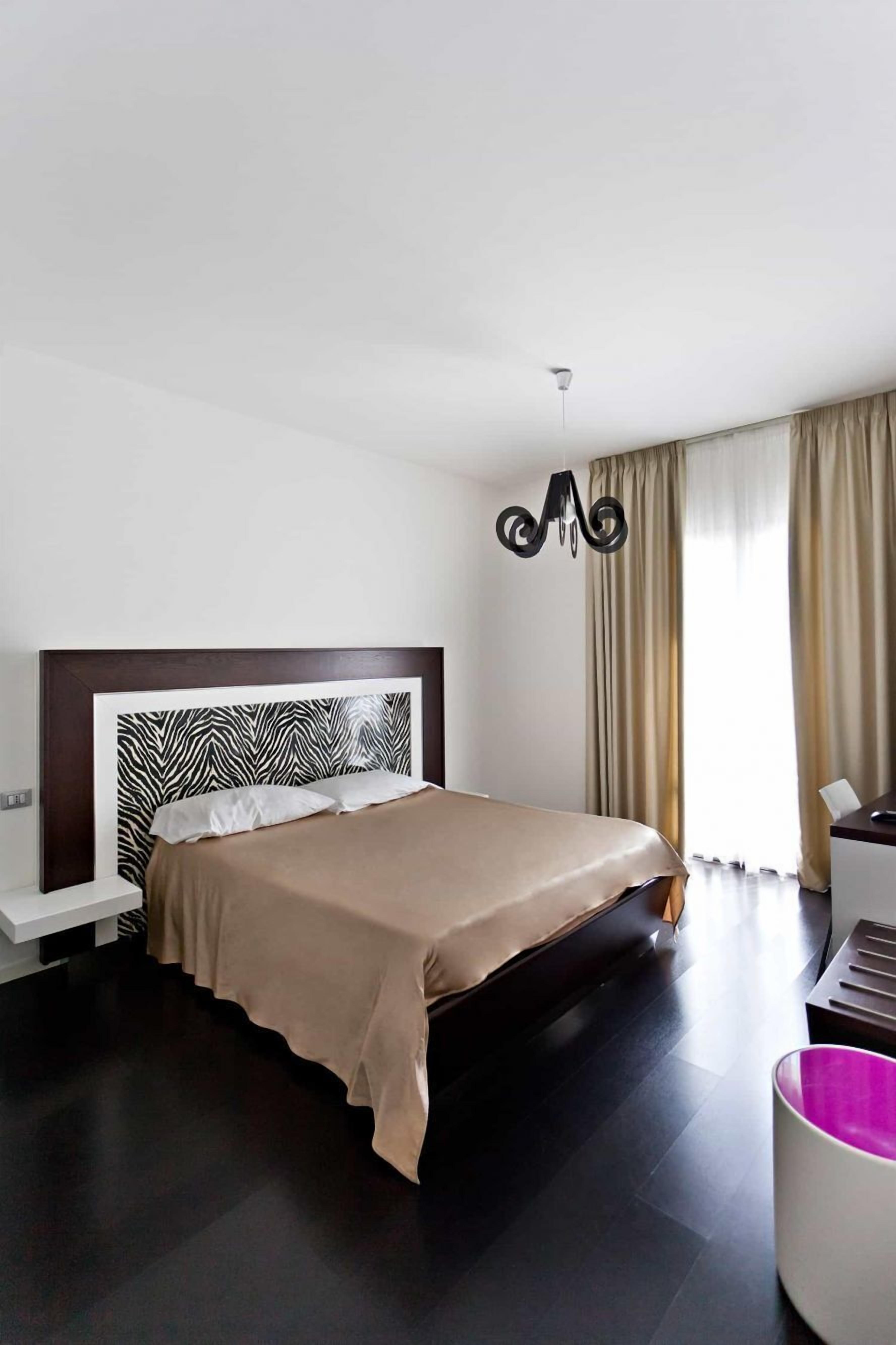 Una habitación de hotel moderna con una cama grande, una mesita de noche y un escritorio.
