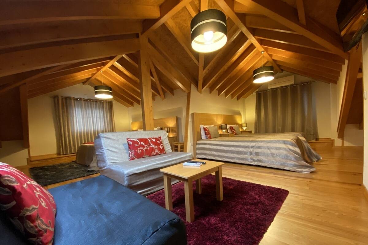 A cozy attic bedroom with a bed, a sofa, and a small table.