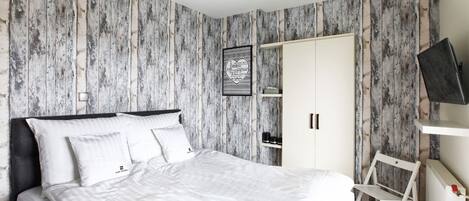 Une chambre à coucher avec un lit, une armoire, une chaise et un téléviseur.