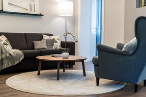 Een woonkamer met een bank, fauteuil, salontafel en vloerlamp.
