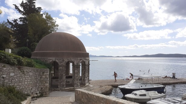 A stone pathway leading to a waterfront area with boats docked.