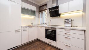 A modern kitchen with white cabinetry, a Bosch oven, and a built-in coffee machine.