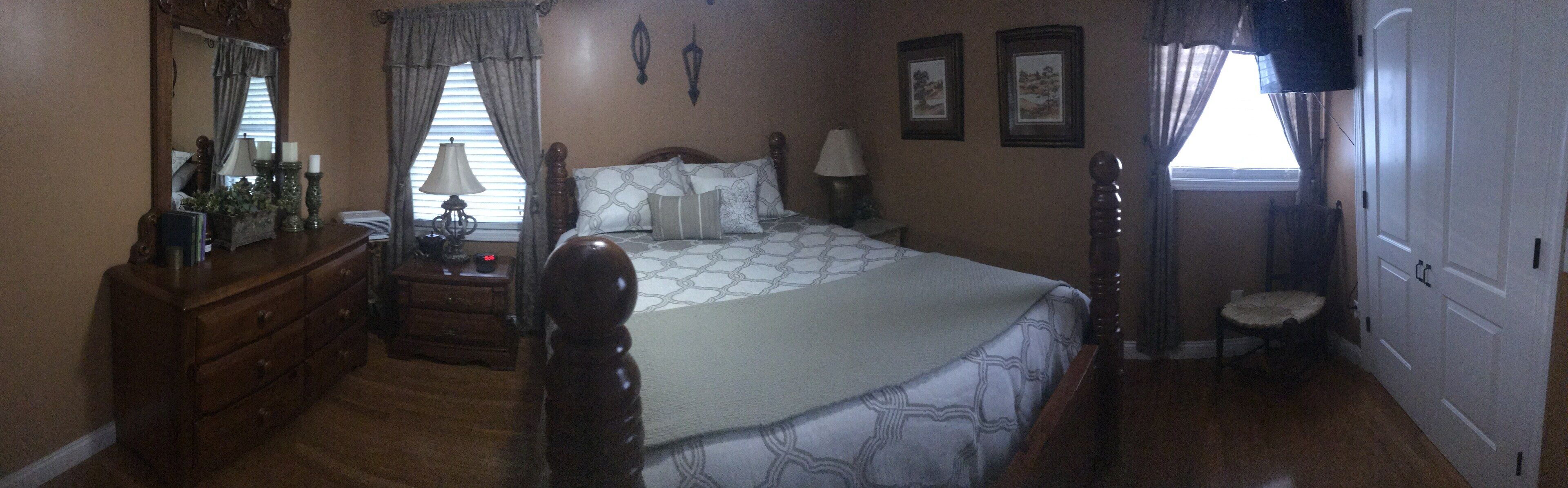 A bedroom with a large bed, wooden dresser, bedside lamps, and a mirror.