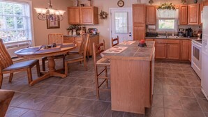 A kitchen with wooden cabinets, a central island, and a dining area with chairs. - EnjoyThis Home in the Mountains  ,5 min walk to the River ,Boone ,West Jefferso (West Jefferson)