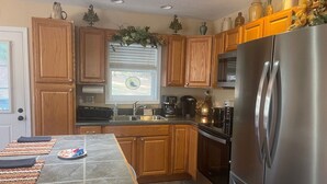 A kitchen with wooden cabinets, a stainless steel refrigerator, a window with a view, and a countertop with a coffee maker. - EnjoyThis Home in the Mountains  ,5 min walk to the River ,Boone ,West Jefferso (West Jefferson)