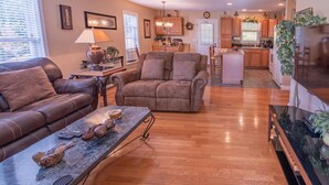 A living room with a leather sofa, a coffee table with decorative items, and a view into the kitchen area. - EnjoyThis Home in the Mountains  ,5 min walk to the River ,Boone ,West Jefferso (West Jefferson)
