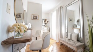 Ein Zimmer mit Holzboden, einer Bank, einem Spiegel und einer Vase mit Blumen.