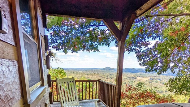 Um deck de madeira com um banco e uma mesa, com vista para uma paisagem deslumbrante.