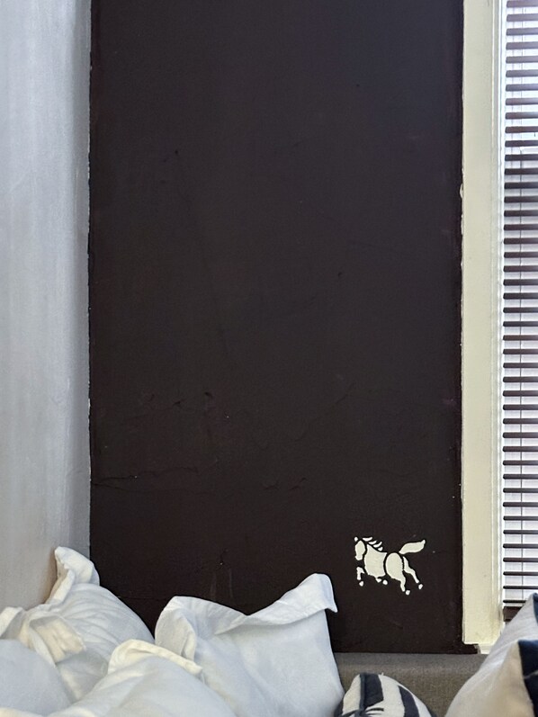 A dark door with a small white sticker of a horse.