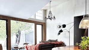 A modern living room with a large window, a dining area with a round table, and a cozy seating area with a fur throw.