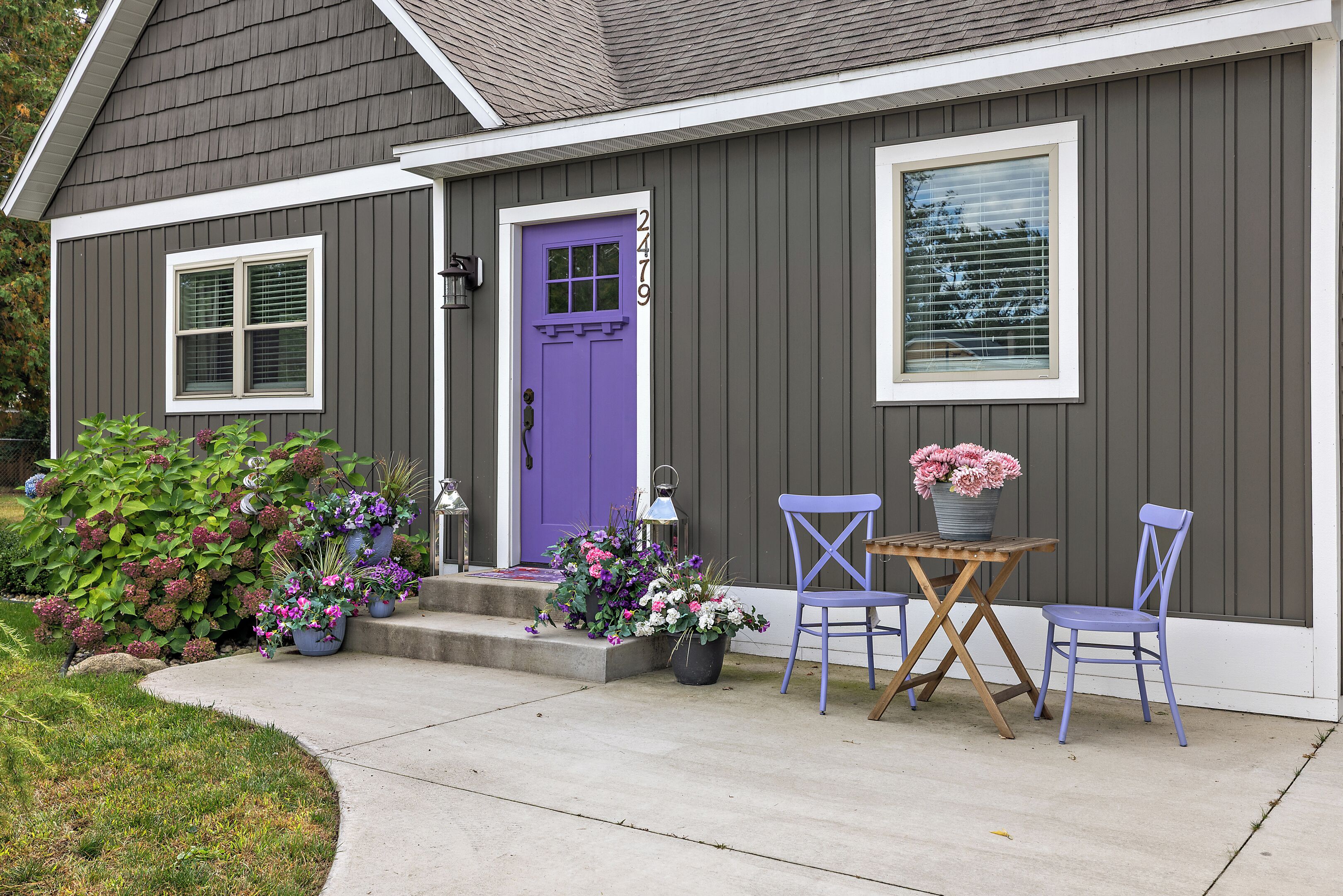 A house with a purple door, a window, and a porch with a table and two chairs.