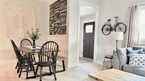 Un soggiorno moderno con zona pranzo, che include un tavolo di legno, sedie, un divano e una bicicletta appesa alla parete.