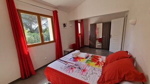 A bedroom with a bed, red curtains, a window, and a door leading to another room. - PALOMBAGGIA VILLA AIR CONDITIONED 4 PERS less than 700 meters from the beach (Porto-Vecchio)