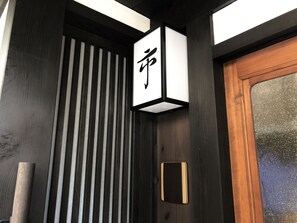 A wooden door with a black and white sign above it. - Kyoyadoya Oyado Ichi (Kyoto)