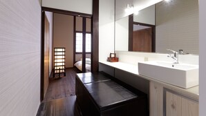 A modern bathroom with a large mirror, a white sink, and a wooden bench.