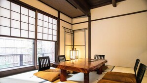 A traditional Japanese room with tatami flooring, a wooden table, and black chairs.