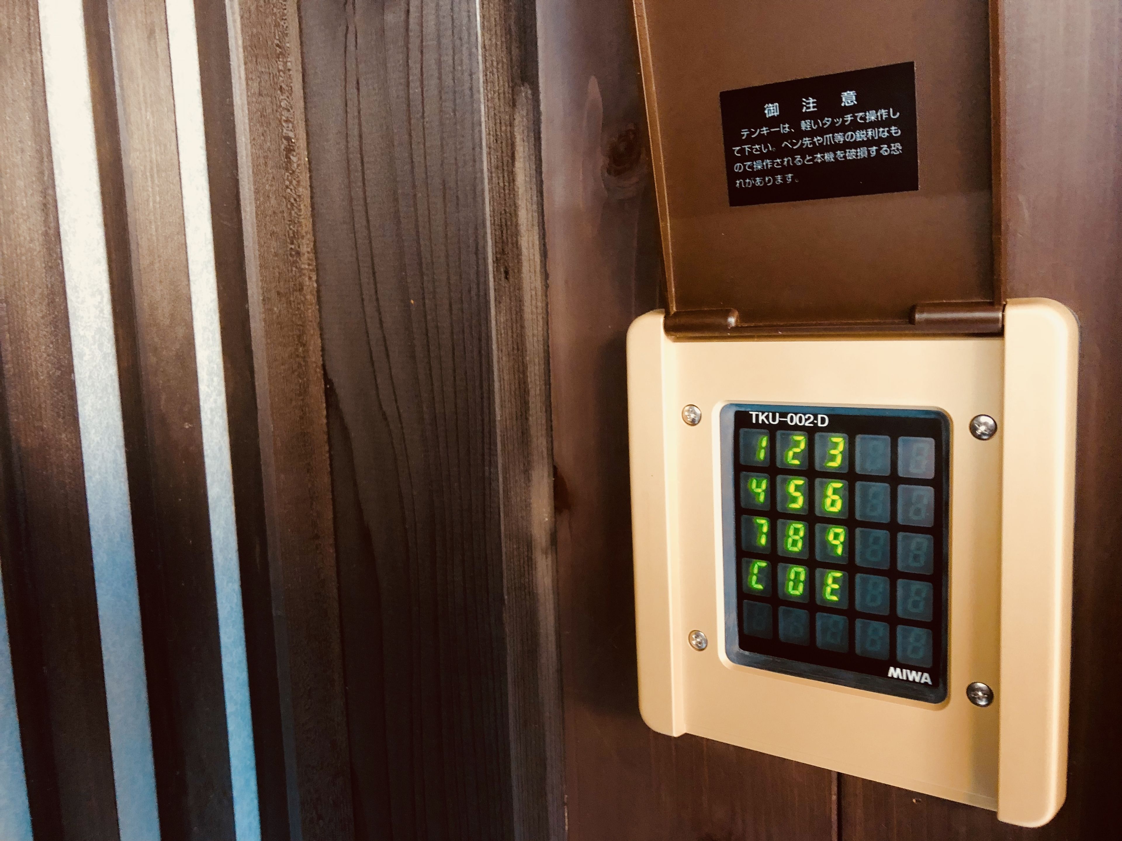 A keypad with a digital display, mounted on a wooden door.