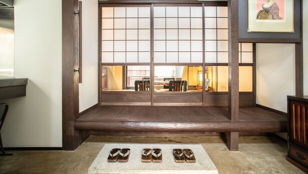 A traditional Japanese room with tatami flooring, a sliding shoji screen, and a framed artwork on the wall.