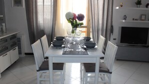 A dining area with a white table set for six, surrounded by white chairs. - Raffy's House Pompeii (Scafati)