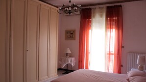 A bedroom with a large bed, a nightstand, a table with a lamp, and a wardrobe. - Raffy's House Pompeii (Scafati)