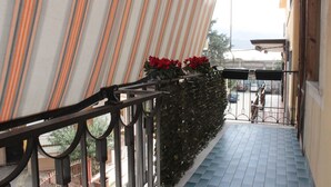 A balcony with striped curtains, a metal railing, and red flowers. - Raffy's House Pompeii (Scafati)
