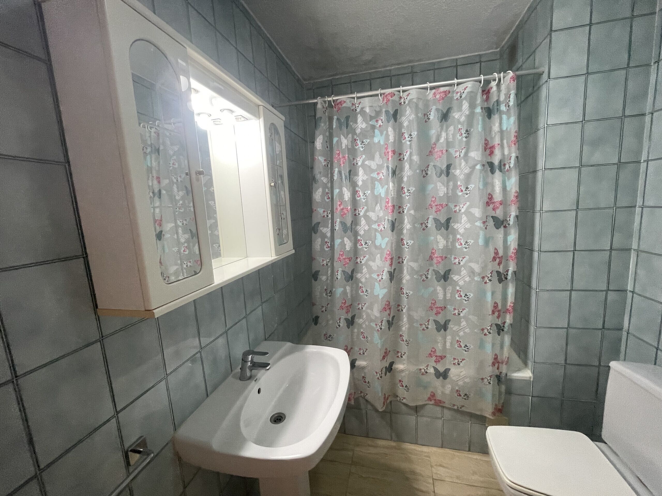 Ein Badezimmer mit Waschbecken, Toilette und Duschvorhang.