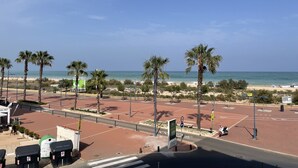 A beachside parking lot with palm trees, a clear sky, and a view of the beach. - Peñismar I D 2-10 (Peñiscola)