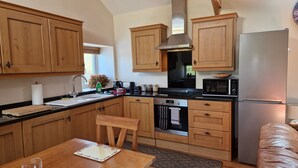 A kitchen with wooden cabinets, a stainless steel refrigerator, a microwave, and a dishwasher. - Watergreens Farm, CA9 3LD  Self-Catering holiday Accommodation in Cumbria (Alston)