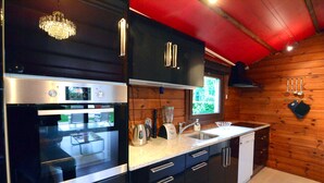 Una cocina moderna con gabinetes negros, electrodomésticos de acero inoxidable y techo rojo.