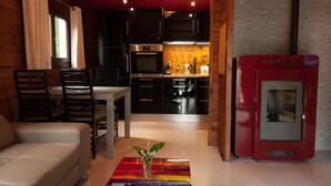 Una cocina moderna con armarios negros, un refrigerador rojo y un comedor con mesa y sillas.