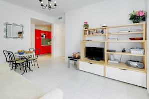 Ein modernes Wohnzimmer mit Fernseher, Bücherregal und Essbereich.