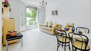 A bright living room with a sofa, dining table, and chairs, a balcony with a view of greenery, and a chandelier. - A beautiful apartment tastefully decorated ... (Nice)