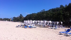 A beach with white canopies and blue lounge chairs.