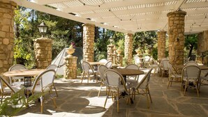 An outdoor patio with stone pillars, wicker chairs, and tables. - The Manor Basket Range (Basket Range)