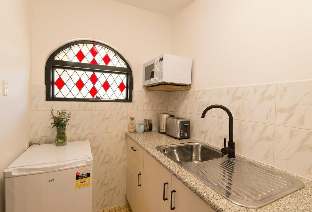 A compact kitchen with a built-in microwave, a stainless steel sink, and a small refrigerator.