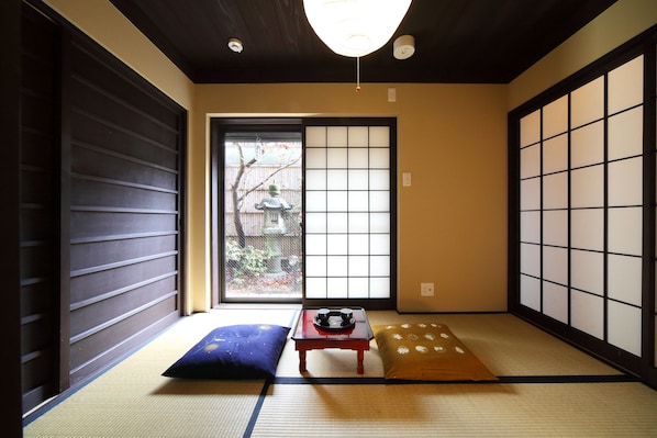 Una habitación japonesa tradicional con suelo de tatami, puertas correderas y vistas al exterior.