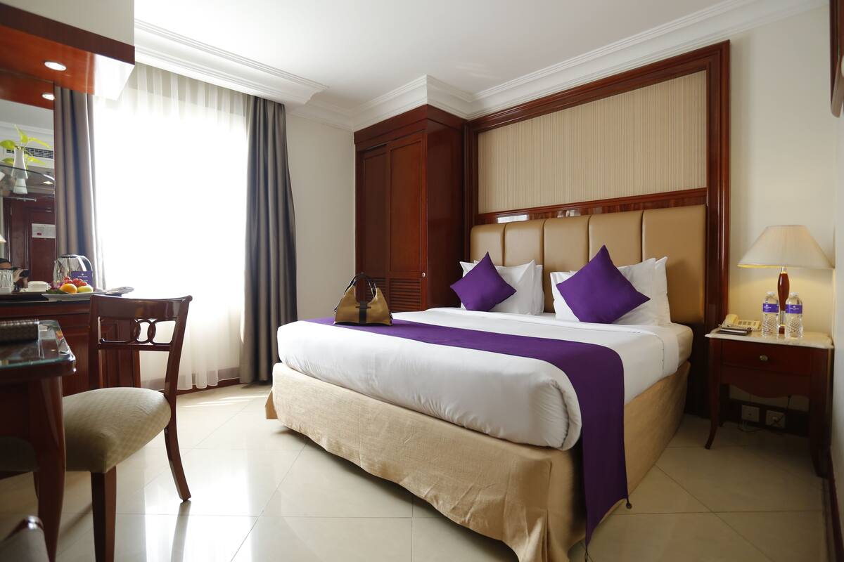 Una habitación de hotel con una cama grande, un escritorio y una silla.