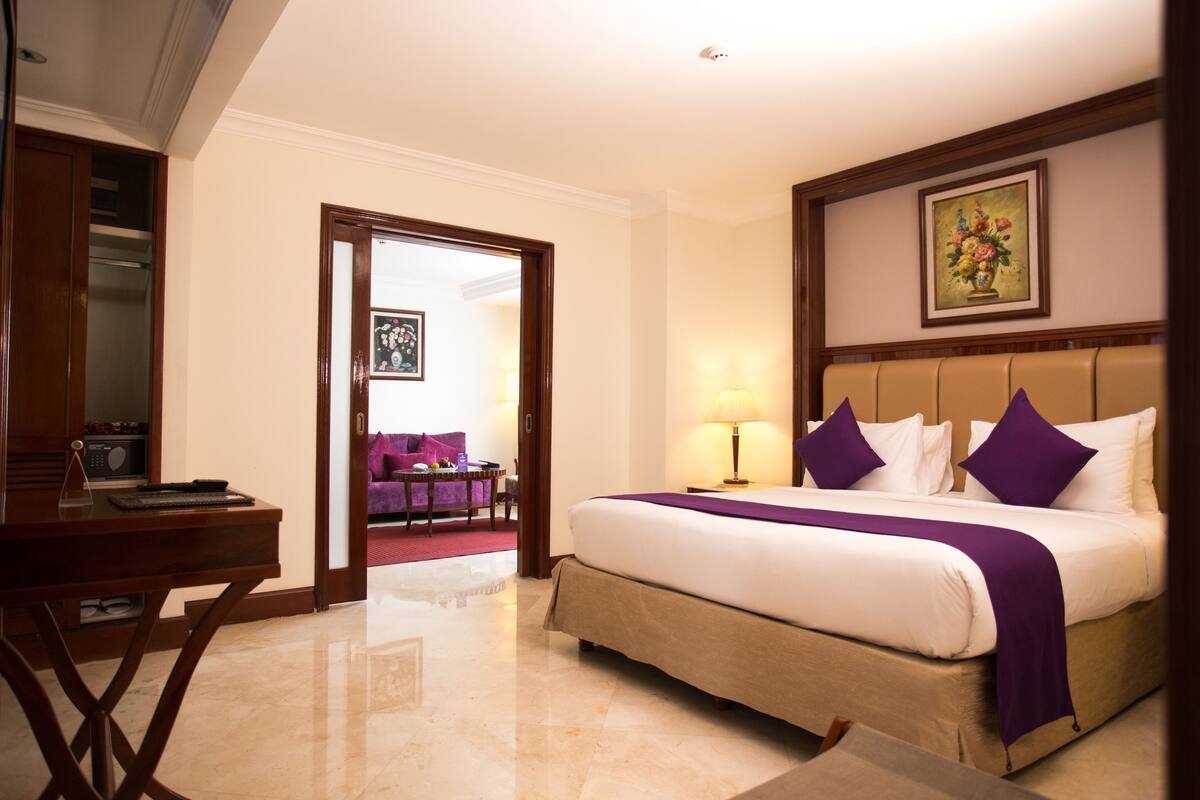 Una habitación de hotel con cama, escritorio, silla y puerta que da a otra habitación.