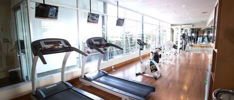 A gym with treadmills, exercise bikes, and a mirrored wall.