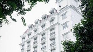 Un hotel de varios pisos con fachada blanca, varios balcones y una entrada cubierta.