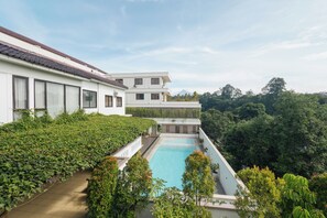 Un edificio moderno de dos pisos con piscina y abundante vegetación.