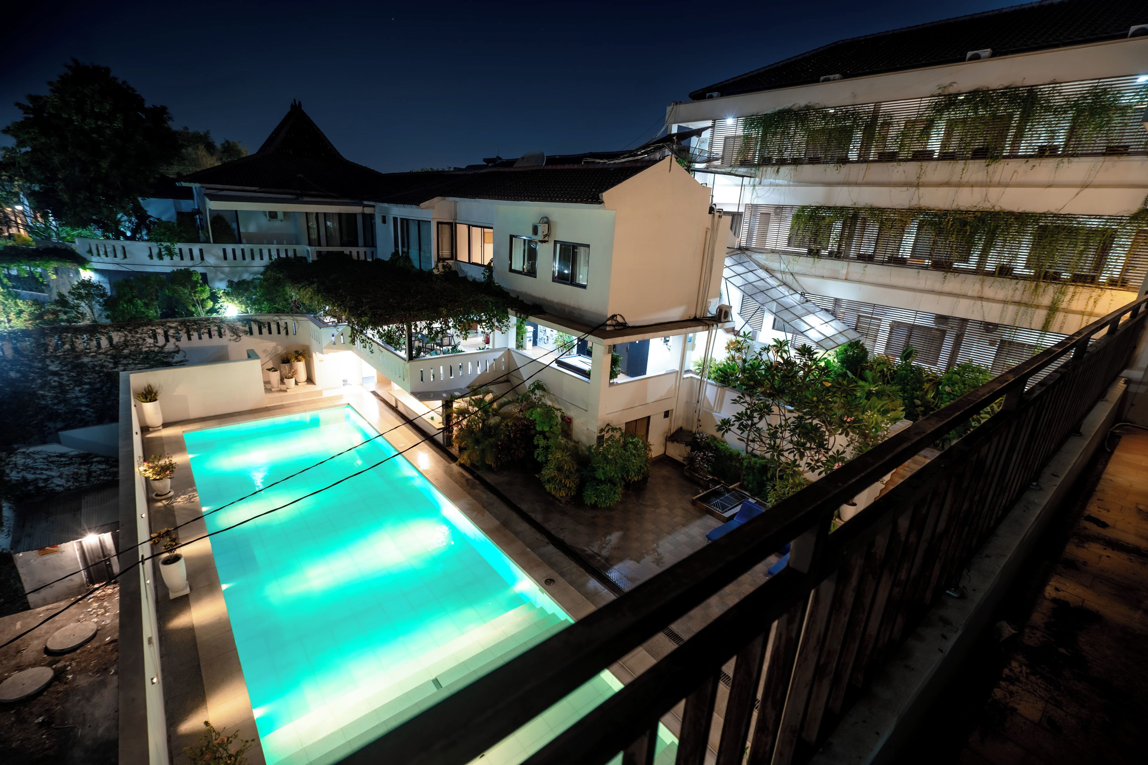 A swimming pool with a view of a multi-story building with balconies and a garden area.