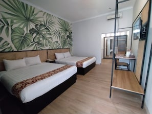 Habitación de hotel con dos camas, un escritorio y un espejo.