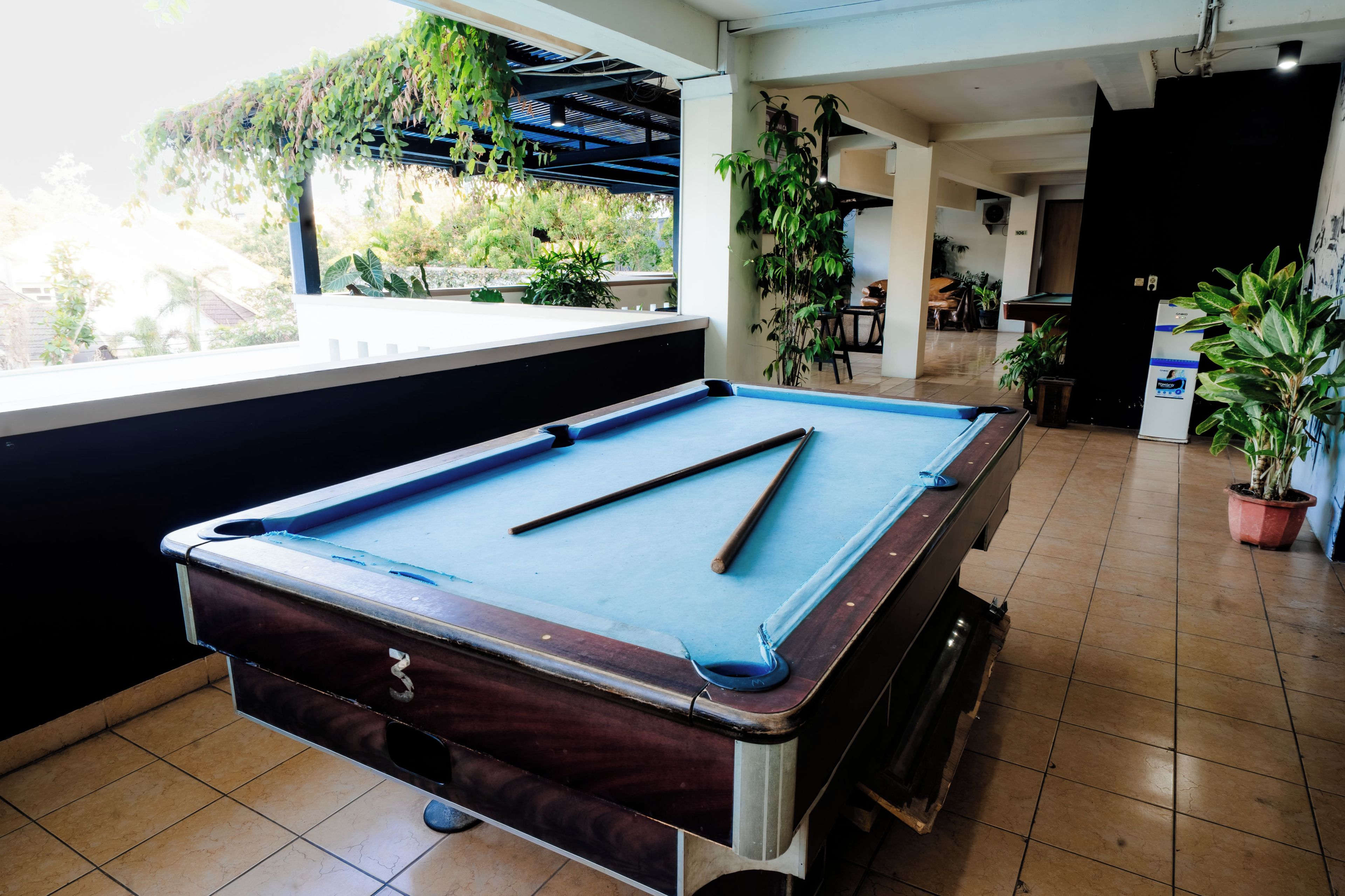 A pool table in a room with a view of greenery outside.