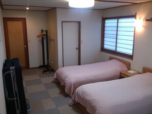 A hotel room with two beds, a wardrobe, a coat rack, and a window with blinds. - Villa Kubota (Nozawaonsen)