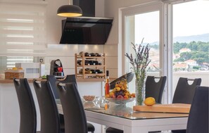 A modern kitchen with a dining area, a wine rack, and a view of the city.