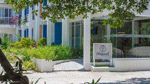 Un edificio con un letrero que dice "Dhiquveli Maldives" y un estilo arquitectónico moderno con ventanas de vidrio y contraventanas azules.