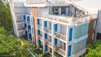 A multi-story hotel with balconies, outdoor seating, and a garden area.