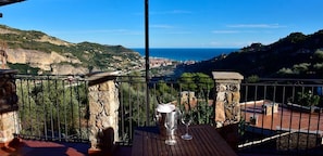 A balcony with a stone railing, a metal table, and a metal bucket.